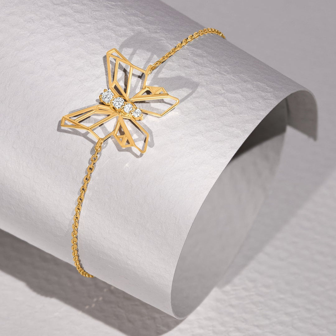 Gold bracelet with a butterfly design on a light gray background