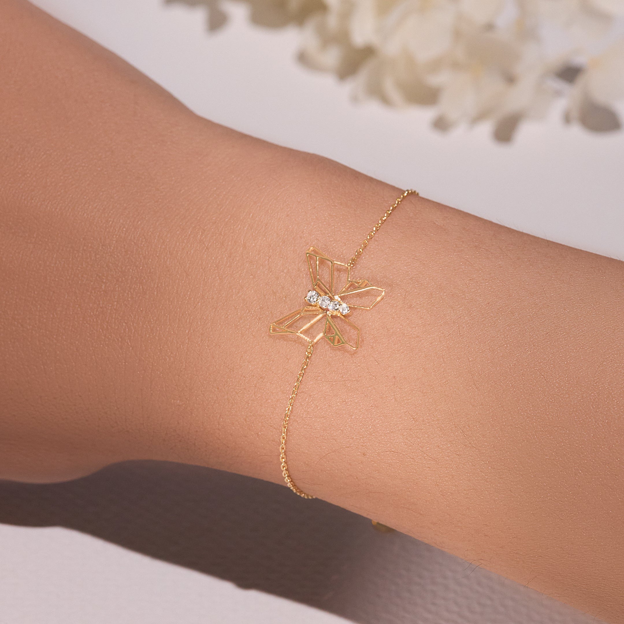 Gold butterfly bracelet on a wrist with a soft background