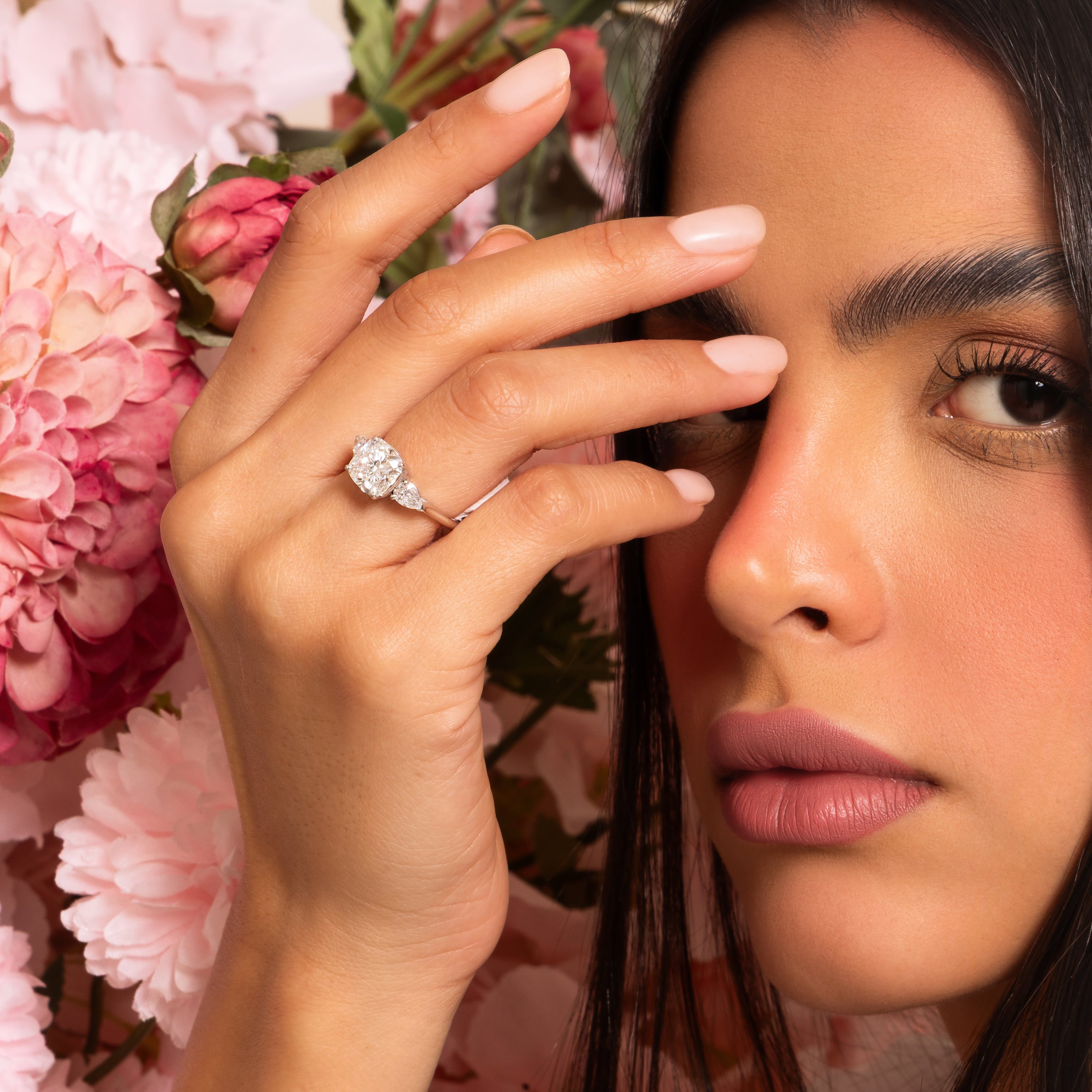 Woman wearing a diamond ring with pink flowers in the background