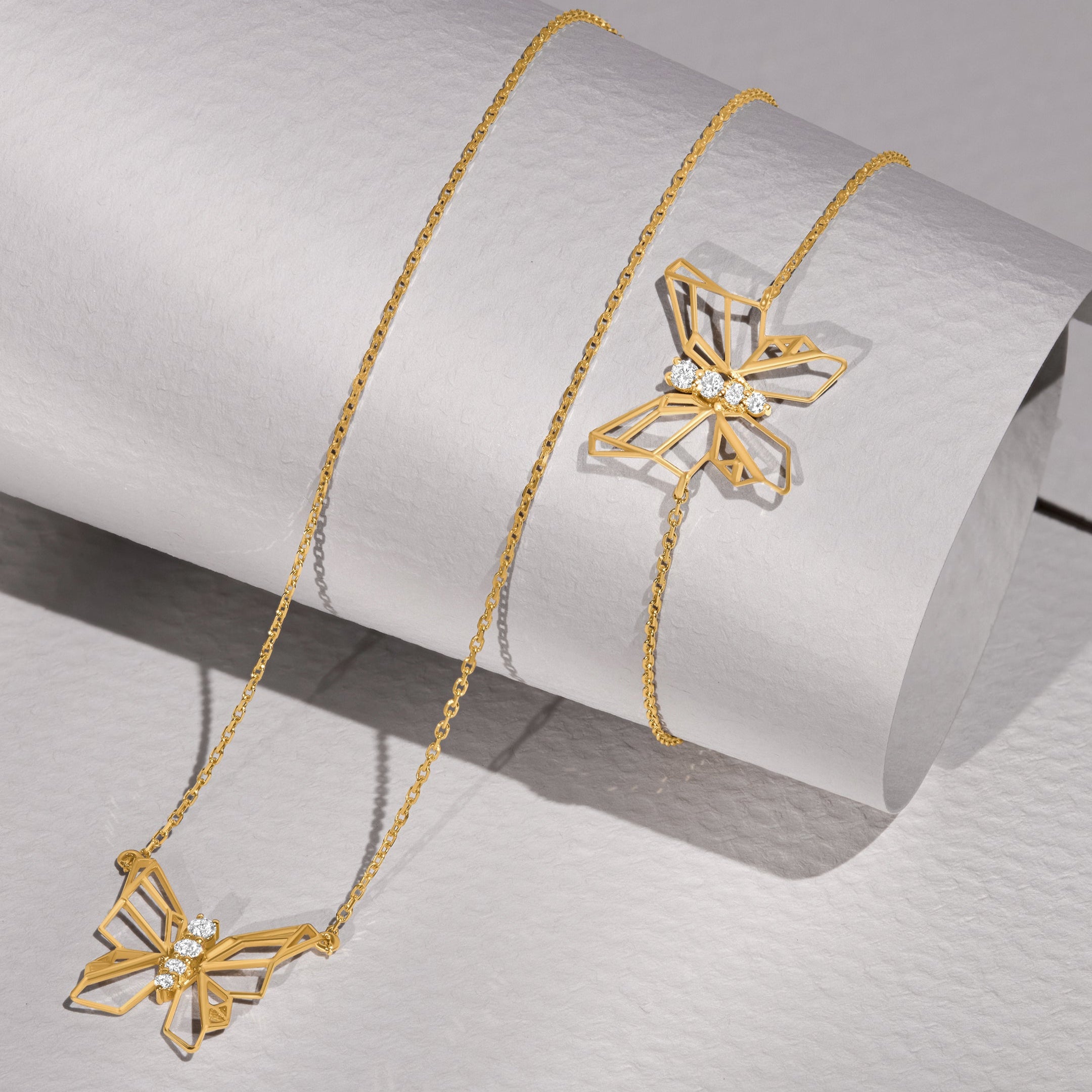 Gold necklace with butterfly pendants on a light gray background